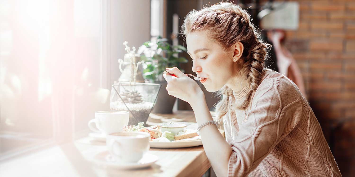 Woman sits in a cafe and eats lunch