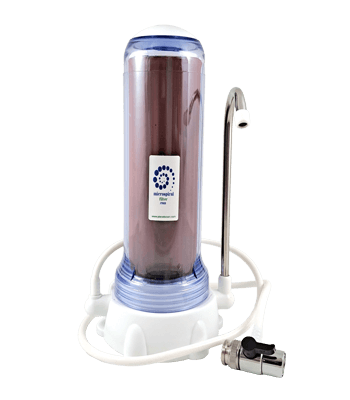Water filter with transparent casing and white base, connected with a white hose and metal tap adapter for kitchen faucet installation.