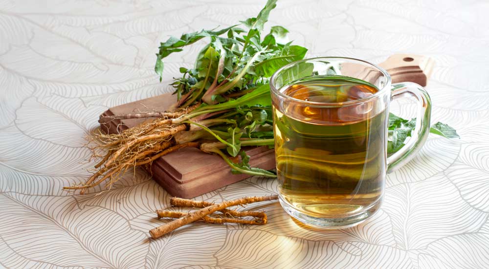 Dandelion roots on a cutting board next to a cup of dandelion tea