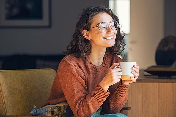 Happy woman enjoying a hot cup of tea in her home