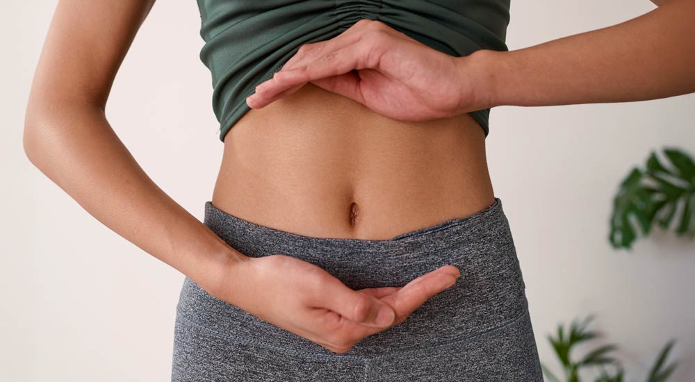 Person formar händer runt magen i en lugn, ljus miljö