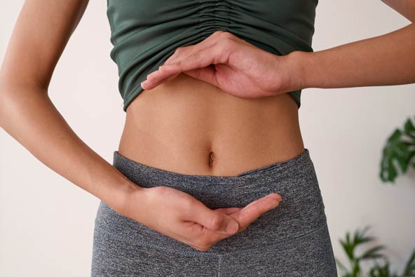 Person formar händer runt magen i en lugn, ljus miljö