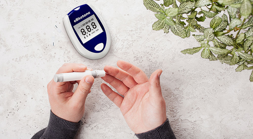 A person pricks their finger with the needle of the ketone meter to measure their ketone level