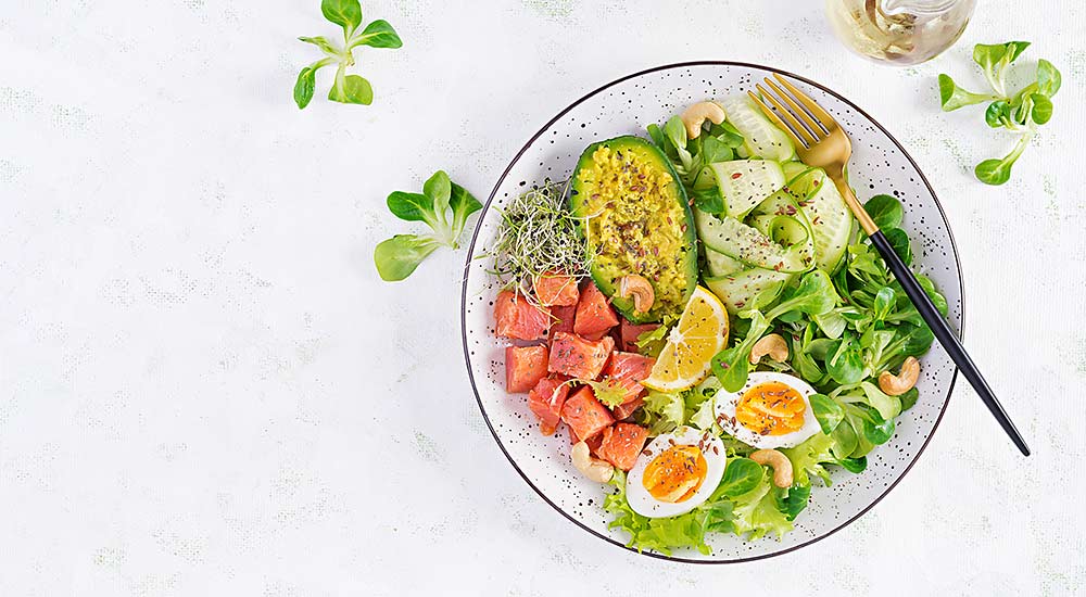 A plate of keto-friendly foods such as avocado, salmon, eggs and vegetables
