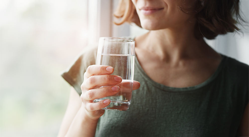 Woman holding a class of clear water and smiling