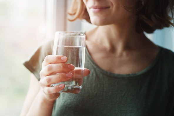 Woman holding a class of clear water and smiling